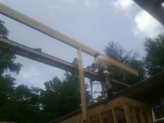 Carpenter setting a ridge beam over a new addition frame — Ice Dam Removal by Roofing Brothers in Universal City