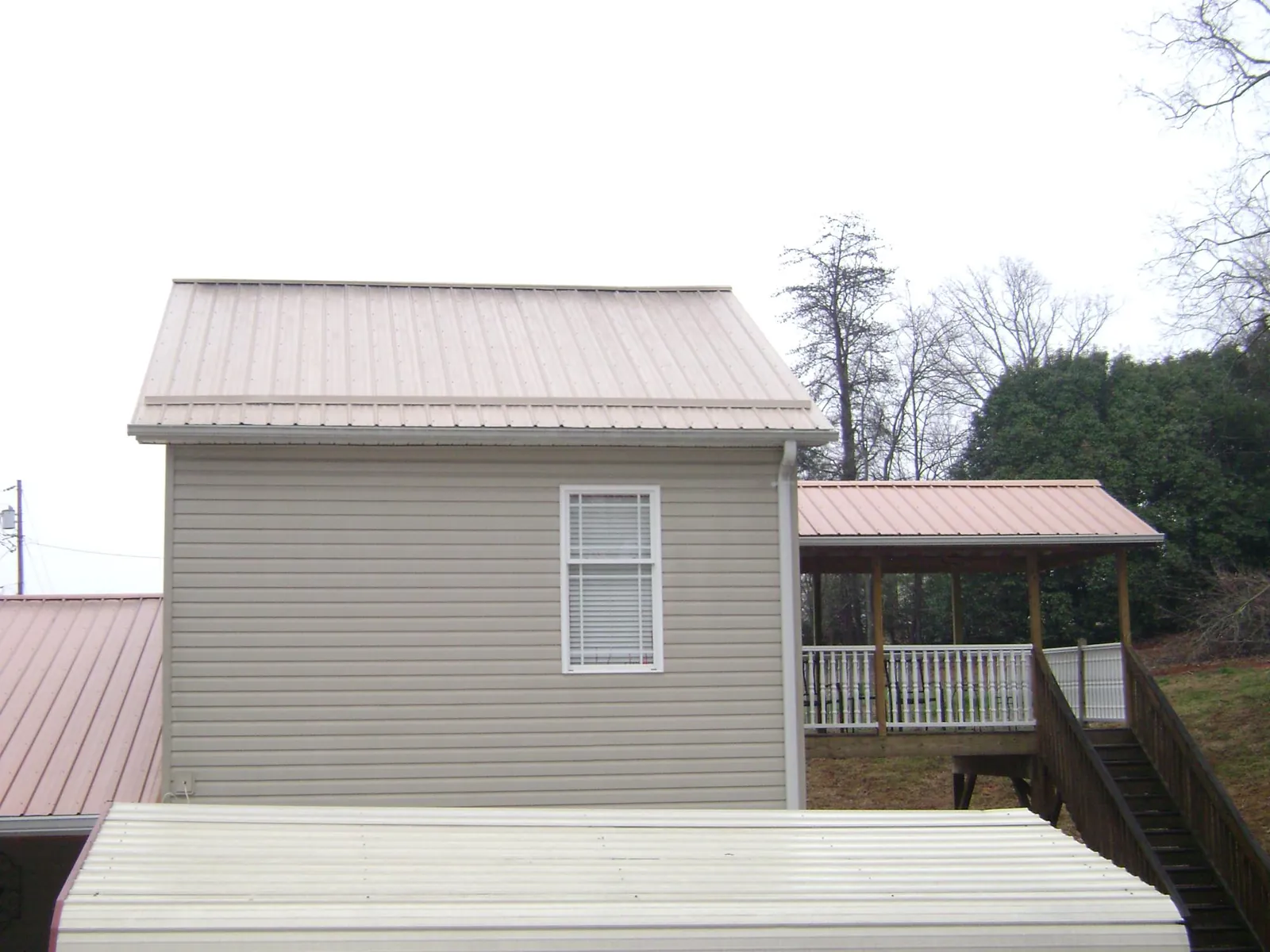 Tan metal roofs on a two story addition and attached porch, from a Roof Replacement job in Universal City