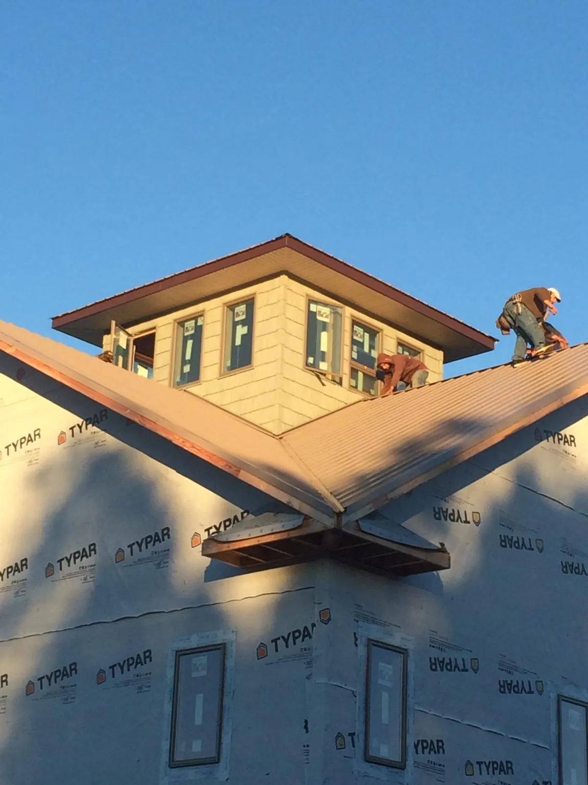 Roofers working around a rooftop cupola on a new metal roof at sunset — Roof Waterproofing in Universal City by Roofing Brothers